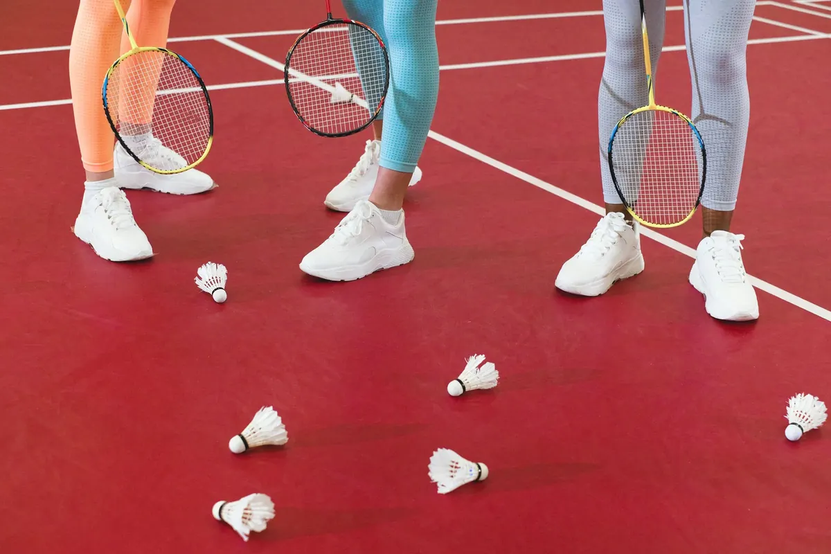 Badminton rackets and shuttlecocks lying on a red court
